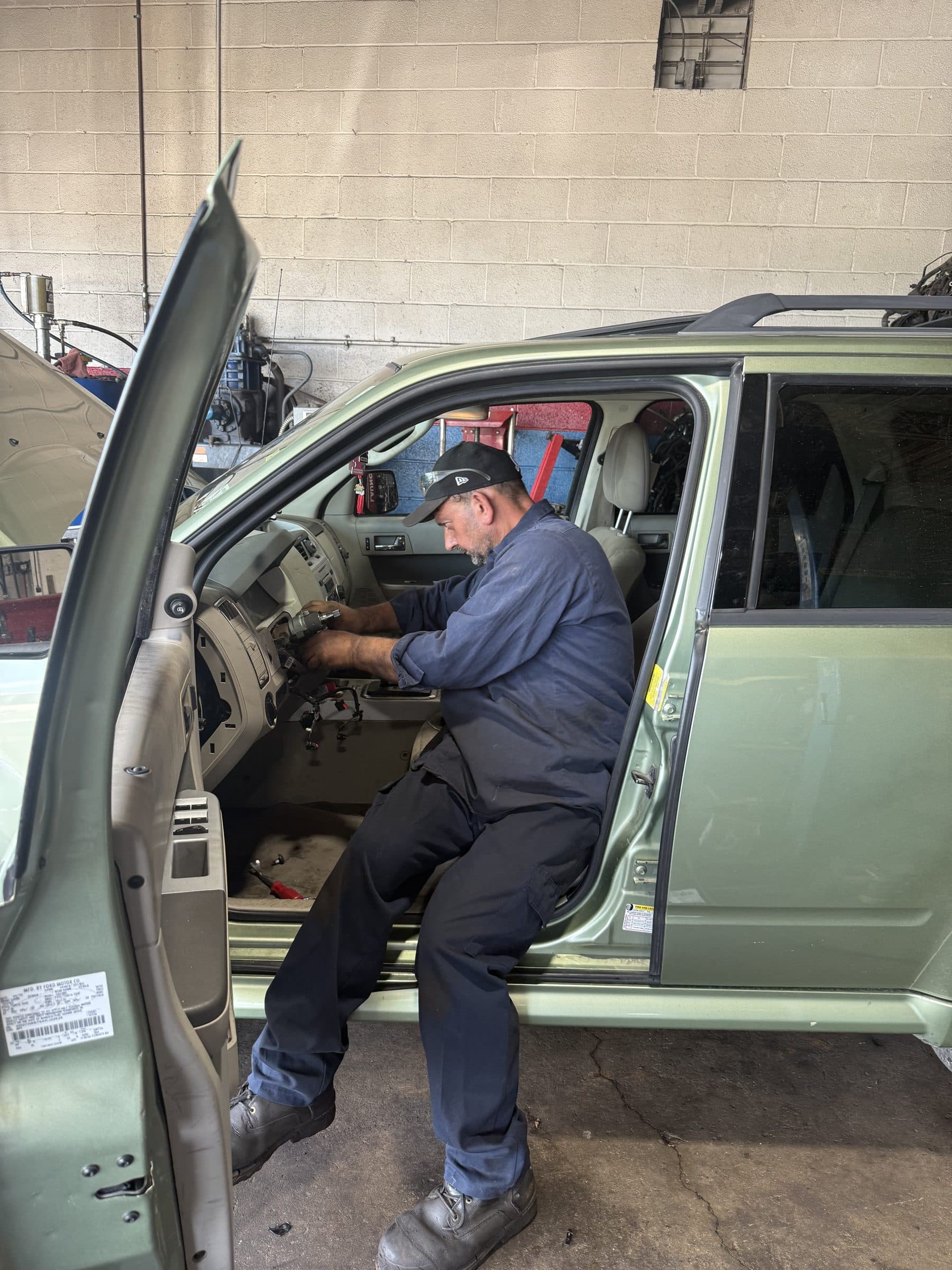 A technician working inside a vehicle cabin