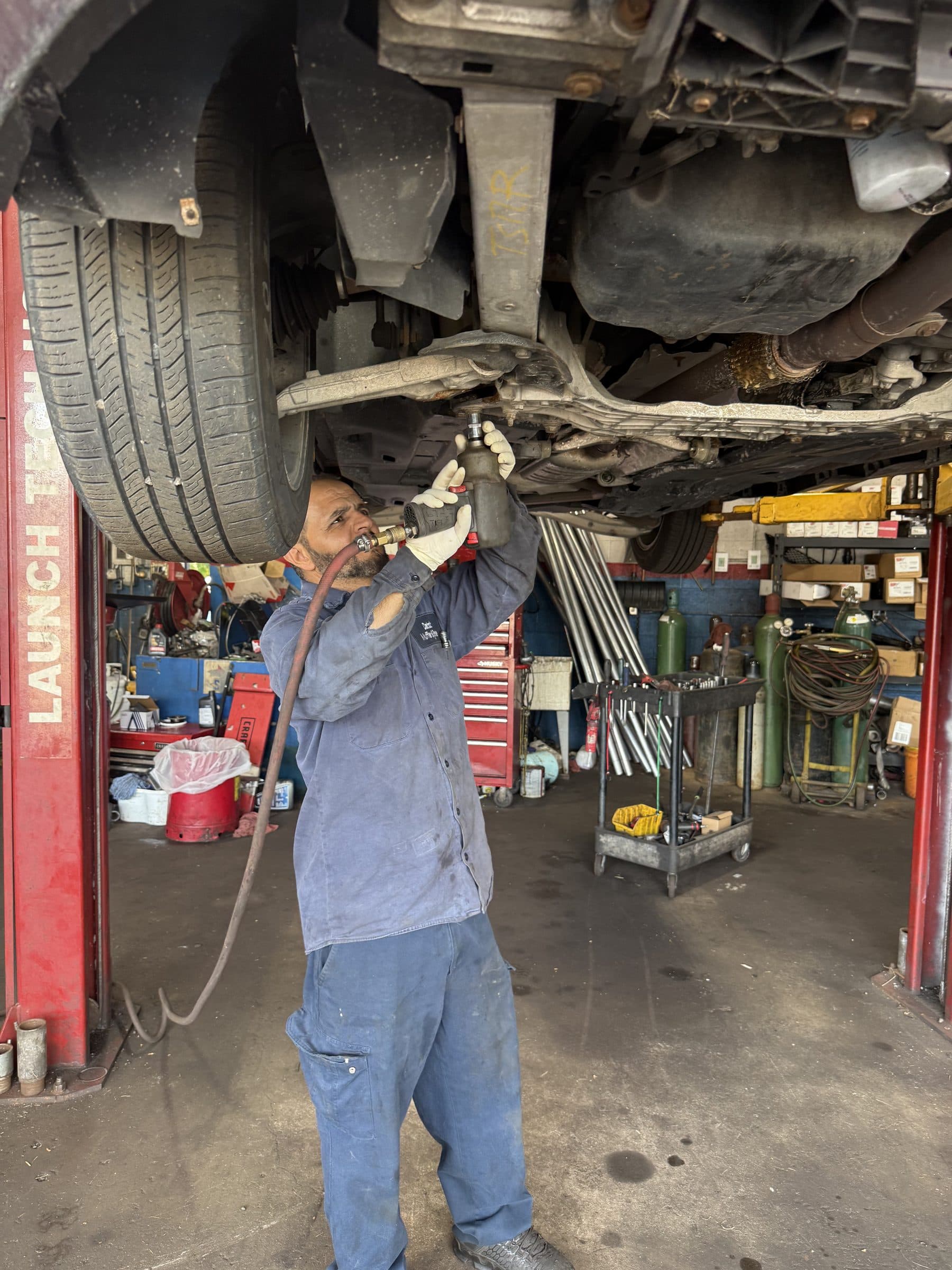 A technician working underneath a vehicle raised on the lift