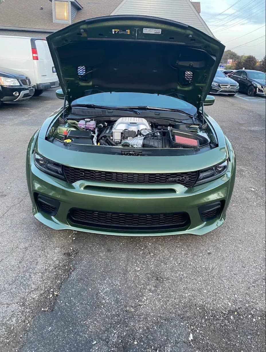 A Dodge Charger SRT with the hood raised showing the supercharged engine